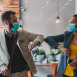 Two employees wearing COVID-19 masks at work, return to work during COVID-19